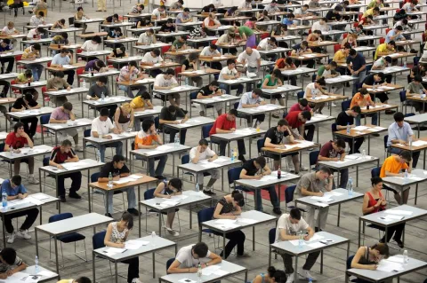 A room of students on desks sitting an exam